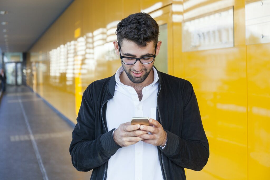 Smiling young businessman using cell phone